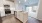 Kitchen island with white cabinets and white marble looking into carpeted living room 