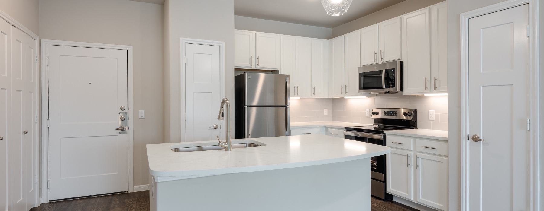 A bright kitchen with an island with white quartz countertops and white cabinets